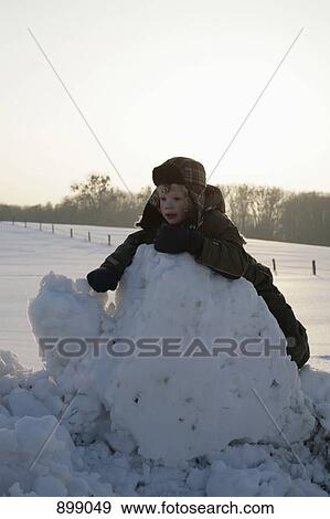 Stock Photo - A child leaning against a pile of snow. Fotosearch