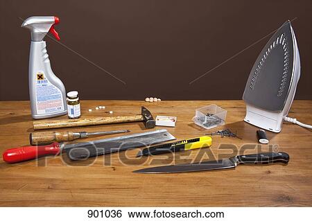 Stock Photograph - A child's fingers grasping a table full of dangerous objects, studio shot. Fotosearch