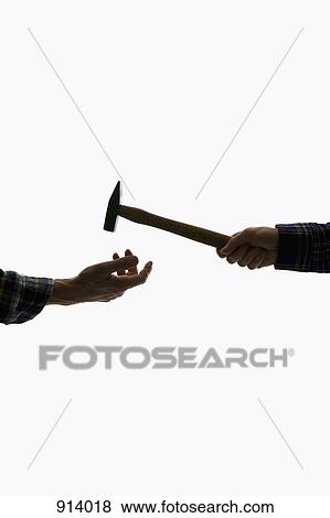 Stock Photo - A construction worker handing a hammer to another worker, focus on hands. Fotosearch