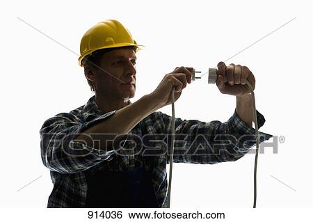 Stock Photograph - A construction worker putting a plug into an extension cord. Fotosearch