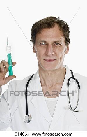 A doctor holding up a syringe View Large Photo Image Stock Photo - A doctor holding up a syringe. Fotosearch