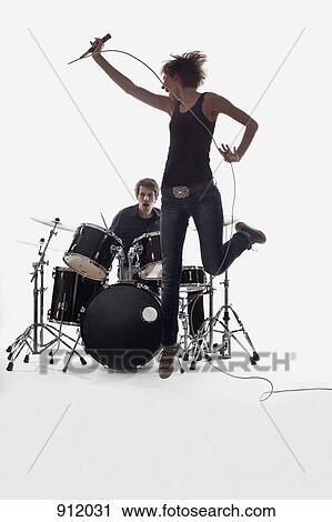 A female singer jumping and a man on the drums performing, studio shot, white background, back lit View Large Photo Image Stock Image - A female singer jumping and a man on the drums performing, studio shot, white background, back lit. Fotosearch