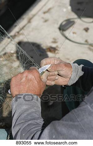 A fisherman cutting a fishing net, focus on hands View Large Photo Image Stock Photography - A fisherman cutting a fishing net, focus on hands. Fotosearch