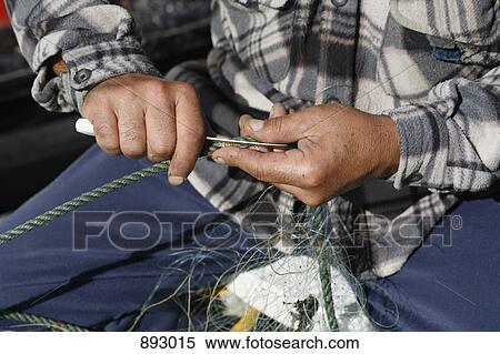 Stock Photography - A fisherman cutting a rope, close-up, focus on hands. Fotosearch