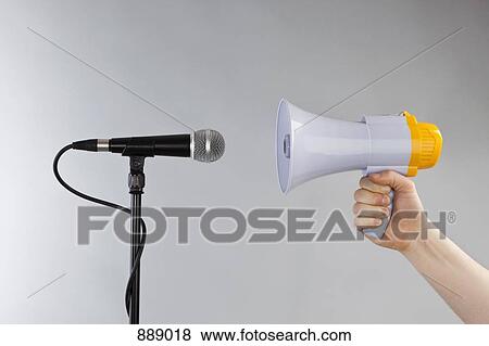 A hand holding a megaphone to a microphone View Large Photo Image Stock Photo - A hand holding a megaphone to a microphone. Fotosearch