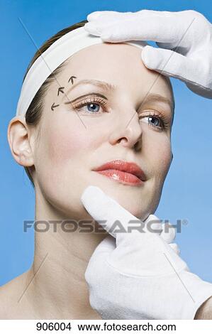 A healthcare worker, detail of hands, preparing a woman for plastic surgery, headshot View Large Photo Image Picture - A healthcare worker, detail of hands, preparing a woman for plastic surgery, headshot. Fotosearch