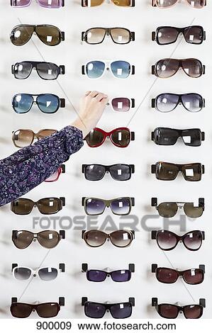 A human hand choosing a pair of sunglasses in an eyewear store View Large Photo Image Stock Photo - A human hand choosing a pair of sunglasses in an eyewear store. Fotosearch