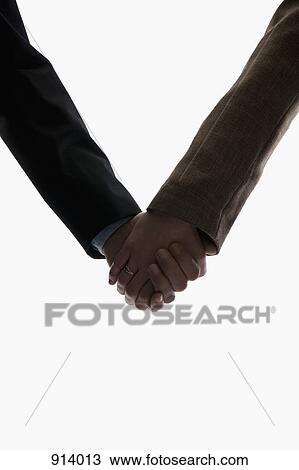 Stock Image - A husband and wife holding hands, focus on hands. Fotosearch