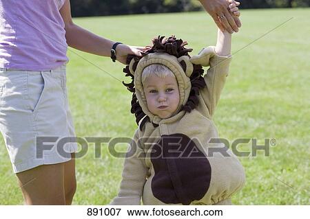 A little boy in a lion costume making a face and holding an adults hand View Large Photo Image Stock Photo - A little boy in a lion costume making a face and holding an adults hand. Fotosearch