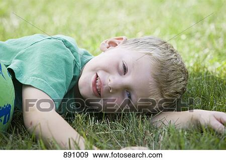 A little boy lying on his side in the grass View Large Photo Image Stock Photo - A little boy lying on his side in the grass. Fotosearch