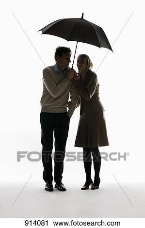 A man and woman huddling under an umbrella View Large Photo Image Stock Image - A man and woman huddling under an umbrella. Fotosearch