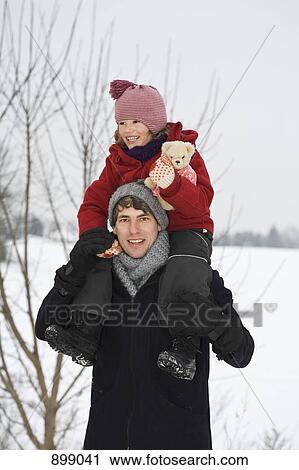 Stock Image - A man carrying his daughter on his shoulders. Fotosearch
