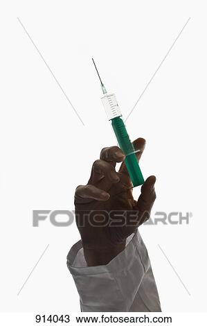 A man holding up a syringe, focus on hand View Large Photo Image Stock Image - A man holding up a syringe, focus on hand. Fotosearch