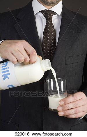 A man in a suit pouring milk in a glass View Large Photo Image Stock Photograph - A man in a suit pouring milk in a glass. Fotosearch