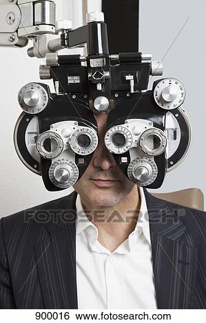 A man looking through a Phoropter during an eye exam View Large Photo Image Stock Photograph - A man looking through a Phoropter during an eye exam. Fotosearch