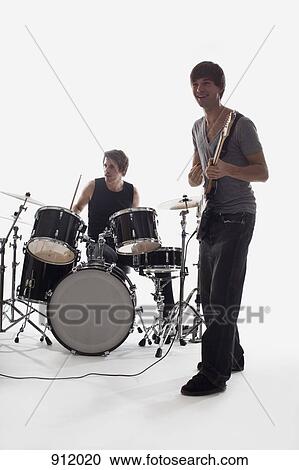 A man playing electric guitar and a man on drums performing, studio shot, white background, back lit View Large Photo Image Stock Image - A man playing electric guitar and a man on drums performing, studio shot, white background, back lit. Fotosearch