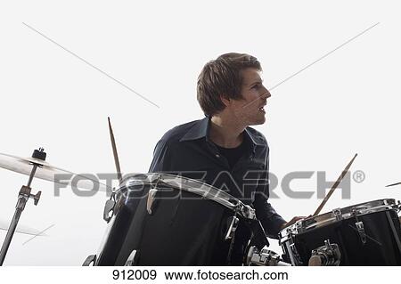 Stock Photo - A man playing the drums, studio shot, white background, back lit. Fotosearch