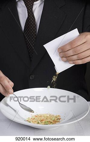 Picture - A man pouring instant soup powder into a bowl. Fotosearch