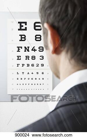 Picture - A man reading an eye chart, over the shoulder view. Fotosearch