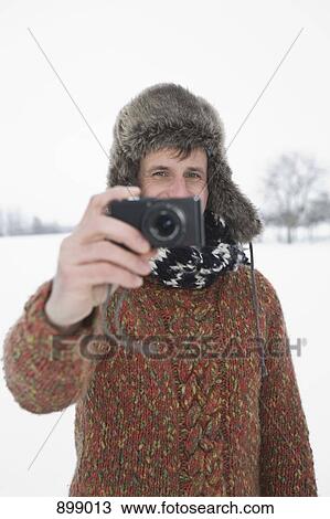 Stock Image - A man taking a picture with a digital camera, outdoors, portrait. Fotosearch