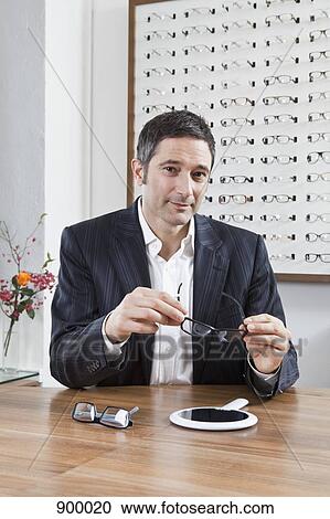 A mature man choosing a pair of eyeglasses in an eyewear store View Large Photo Image Stock Image - A mature man choosing a pair of eyeglasses in an eyewear store. Fotosearch