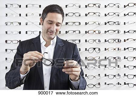 A mature man choosing a pair of eyeglasses in an eyewear store View Large Photo Image Stock Photo - A mature man choosing a pair of eyeglasses in an eyewear store. Fotosearch