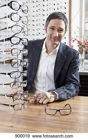 Stock Photo - A mature man choosing a pair of eyeglasses in an eyewear store. Fotosearch