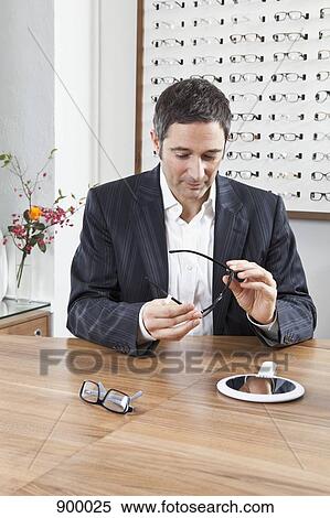 A mature man choosing a pair of eyeglasses in an eyewear store View Large Photo Image Stock Photography - A mature man choosing a pair of eyeglasses in an eyewear store. Fotosearch