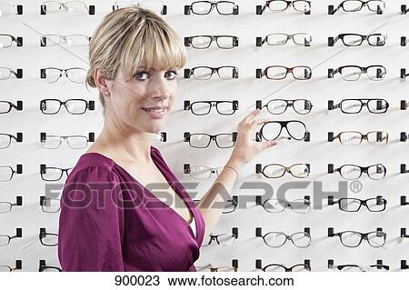 A mid adult woman choosing a pair of eyeglasses in an eyewear store View Large Photo Image Stock Image - A mid adult woman choosing a pair of eyeglasses in an eyewear store. Fotosearch