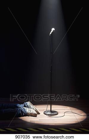 Stock Photography - A Person Lying On A Stage Next To A Spot Lit Microphone. Fotosearch