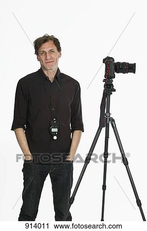 A photographer posing next to his camera on a tripod View Large Photo Image Stock Image - A photographer posing next to his camera on a tripod. Fotosearch