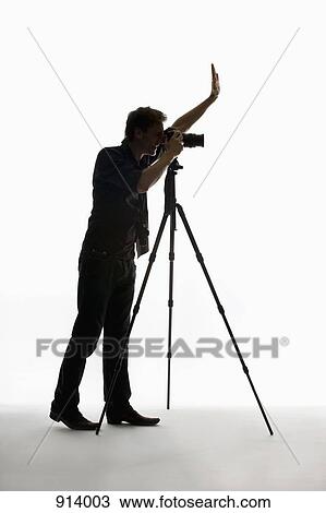 A photographer working with a camera on a tripod View Large Photo Image Stock Image - A photographer working with a camera on a tripod. Fotosearch
