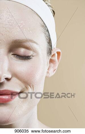 Stock Photography - A serene woman with a wet face and closed eyes. Fotosearch