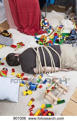 Stock Photograph - A tied up man in a children's playroom. Fotosearch