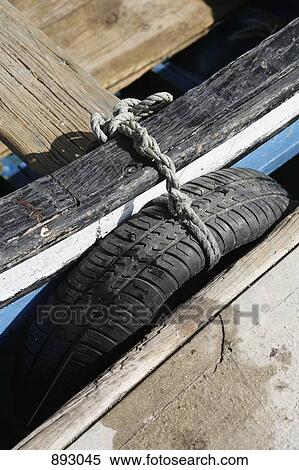 A tire tied to a boat docked at a jetty View Large Photo Image Stock Photography - A tire tied to a boat docked at a jetty. Fotosearch