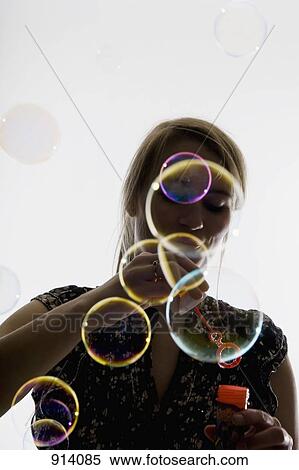Stock Photography - A woman blowing bubbles with a bubble wand. Fotosearch