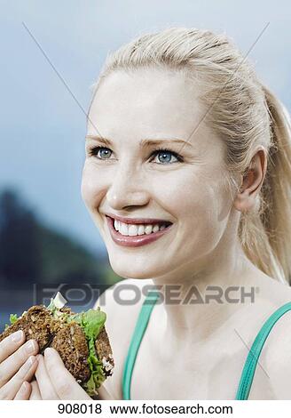 Stock Photo - A woman eating a sandwich on 7-grain bread. Fotosearch