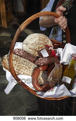 Stock Photo - A woman holding a basket of sausages and bread, focus on basket, Carinthia, Austria. Fotosearch