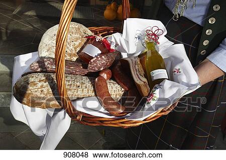 Stock Photo - A woman holding a basket of sausages and bread, focus on basket, Carinthia, Austria. Fotosearch