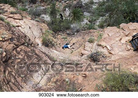 Picture - A Woman Lying At The Bottom Of A Rocky Hill. Fotosearch