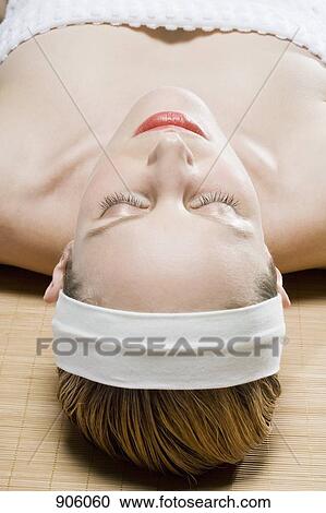 Stock Image - A woman lying on a Tatami mat, eyes closed. Fotosearch