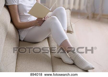 A woman reclining on a couch with a book, focus on low section View Large Photo Image Stock Photo - A woman reclining on a couch with a book, focus on low section. Fotosearch