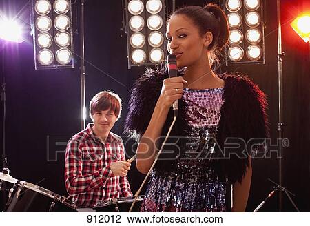 Stock Image - A woman singer accompanied by a man on drums performing on stage. Fotosearch