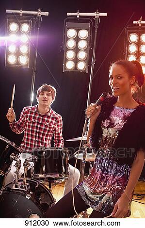 Stock Image - A woman singer accompanied by a man on drums performing on stage. Fotosearch