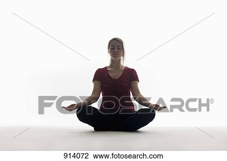 Stock Image - A woman sitting cross-legged, meditating. Fotosearch
