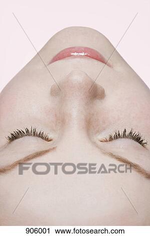 Stock Image - A woman with closed eyes, extreme close up, rear view, lying on back. Fotosearch