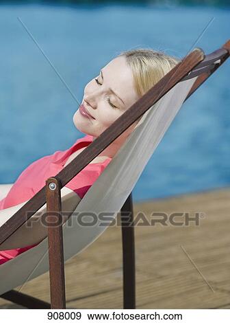 A woman with her eyes closed reclining in a beach chair View Large Photo Image Stock Photo - A woman with her eyes closed reclining in a beach chair. Fotosearch