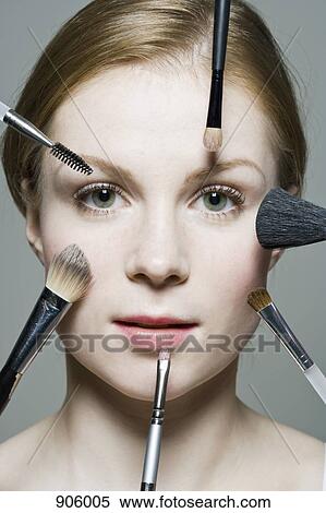 A woman with various make-up brushes applying make-up to her face View Large Photo Image Stock Photography - A woman with various make-up brushes applying make-up to her face. Fotosearch