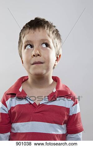 Stock Photo - A young boy looking up and to the side, studio shot. Fotosearch