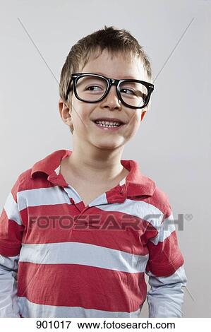 A young boy wearing fake glasses and smiling slyly, studio shot View Large Photo Image Stock Photo - A young boy wearing fake glasses and smiling slyly, studio shot. Fotosearch